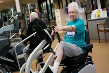 Older adults exercising on stationary bikes in a community fitness center.