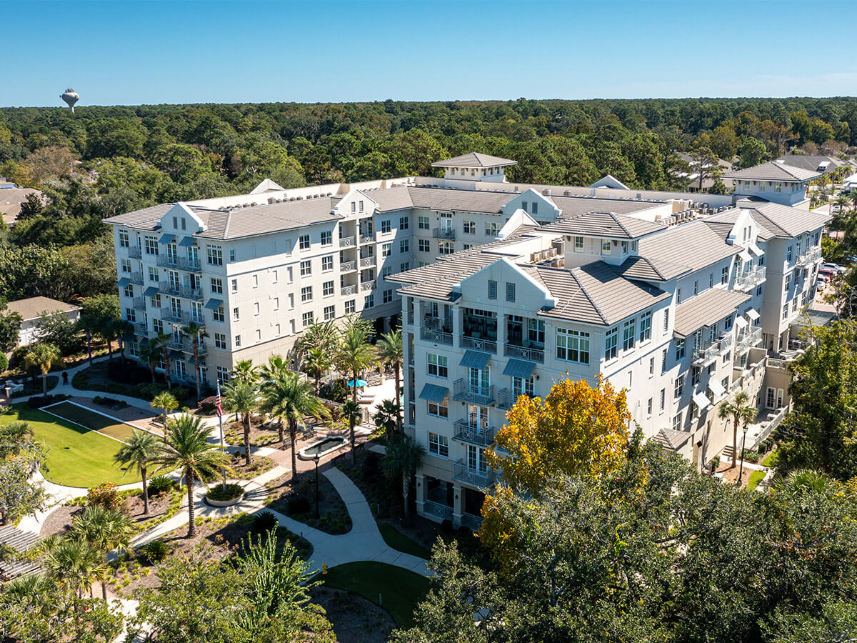 Aerial view of a large residential building surrounded by trees and pathways.