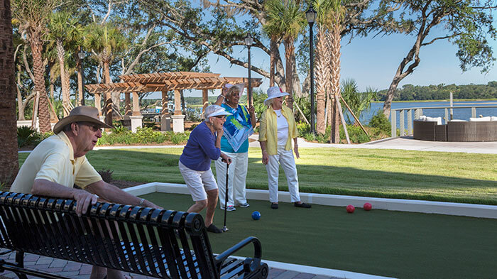 Residents playing bocce ball in a landscaped courtyard with trees and seating.