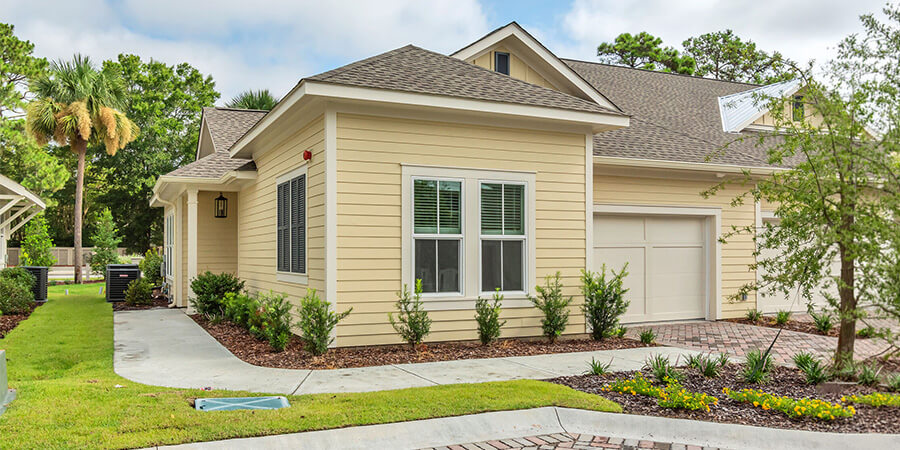Single-story unit with beige siding in a landscaped senior living community.