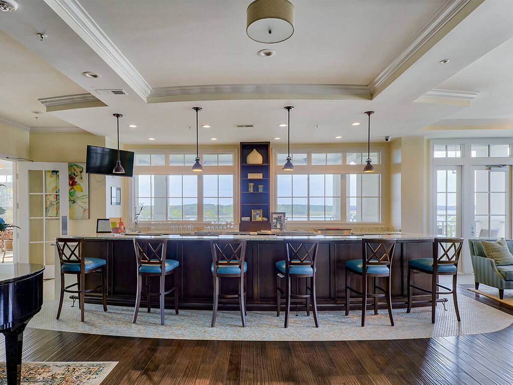 Elegant community lounge with a long bar and high chairs in a senior living unit.