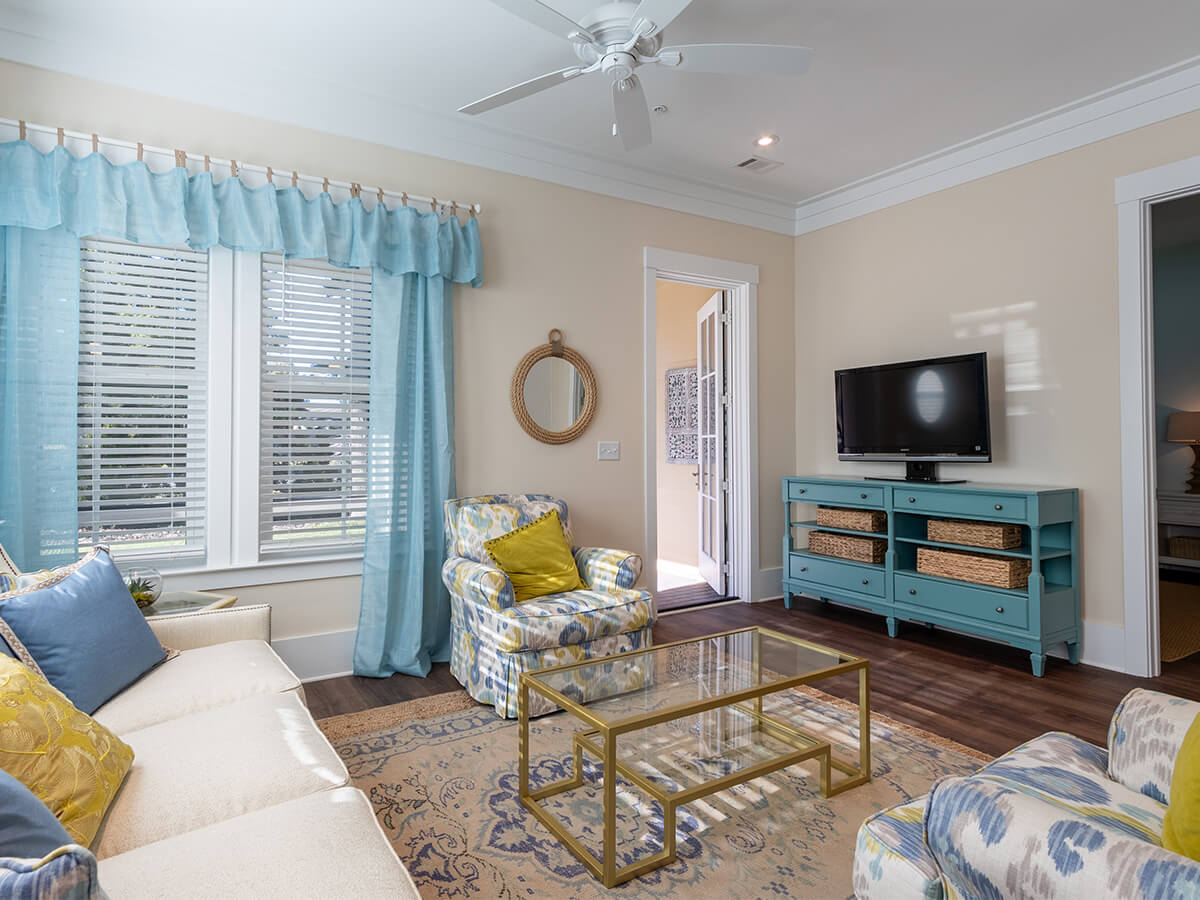 Cozy unit living room with patterned chairs, TV, and blue curtains.