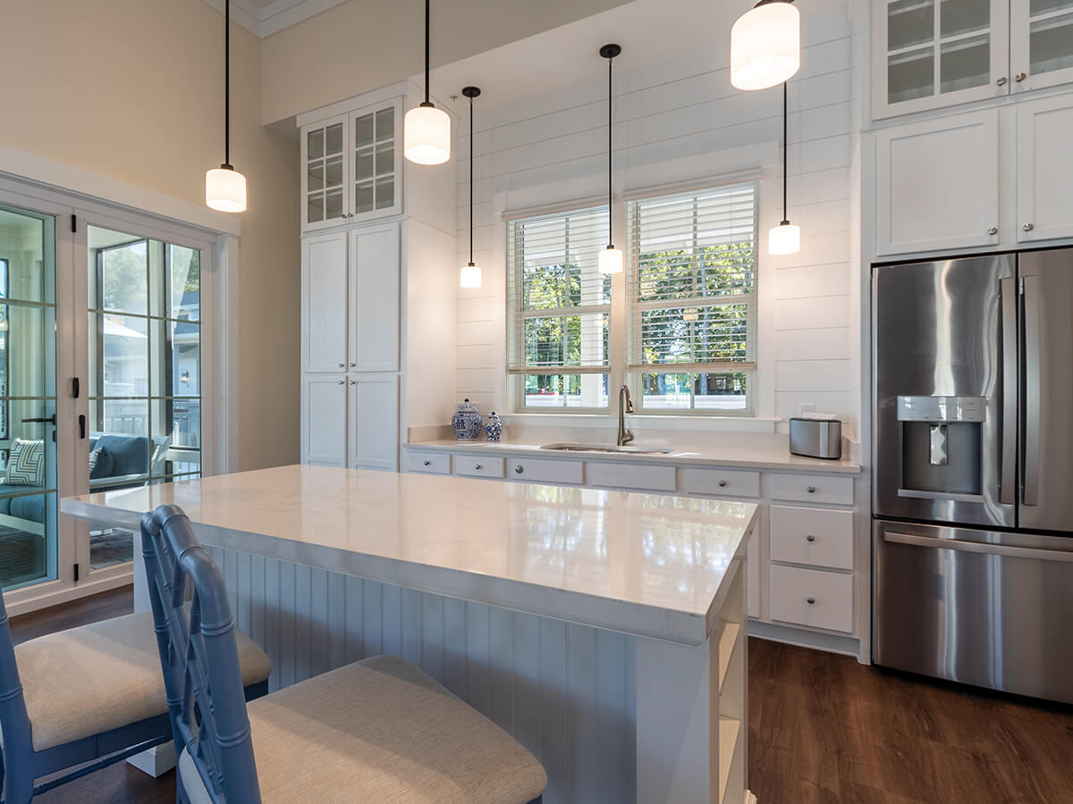 Modern kitchen with white cabinetry, marble countertops, and stainless steel appliances.
