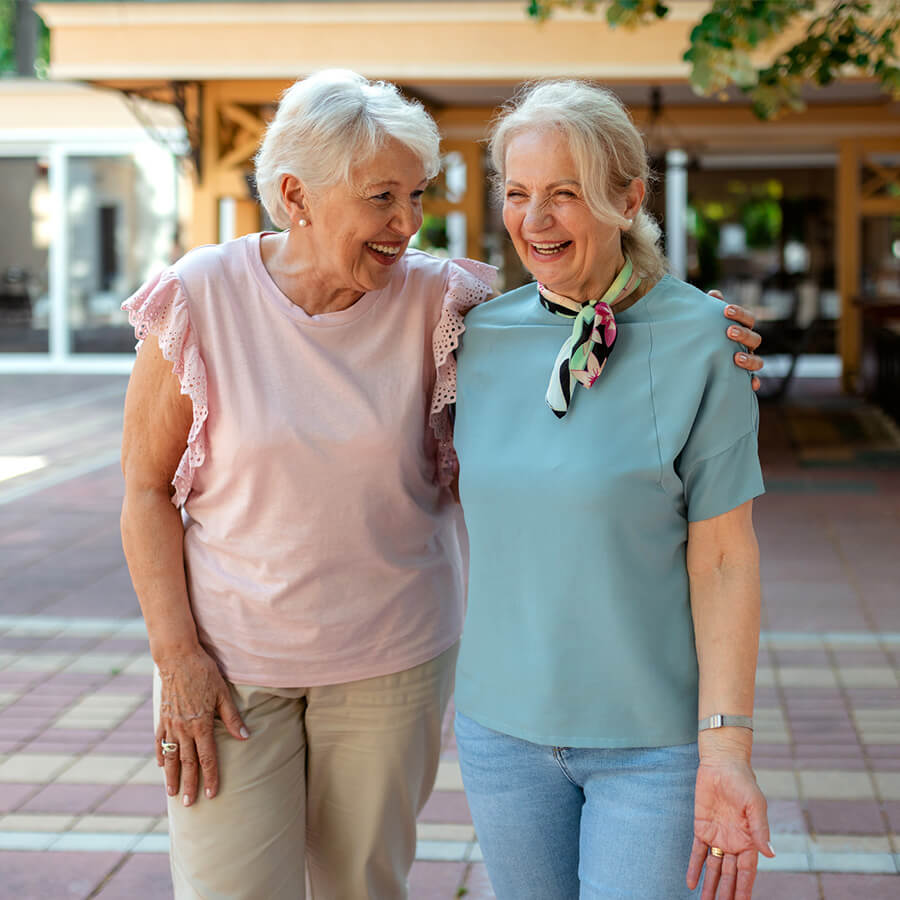 Two elderly women laughing together at a communal courtyard.
