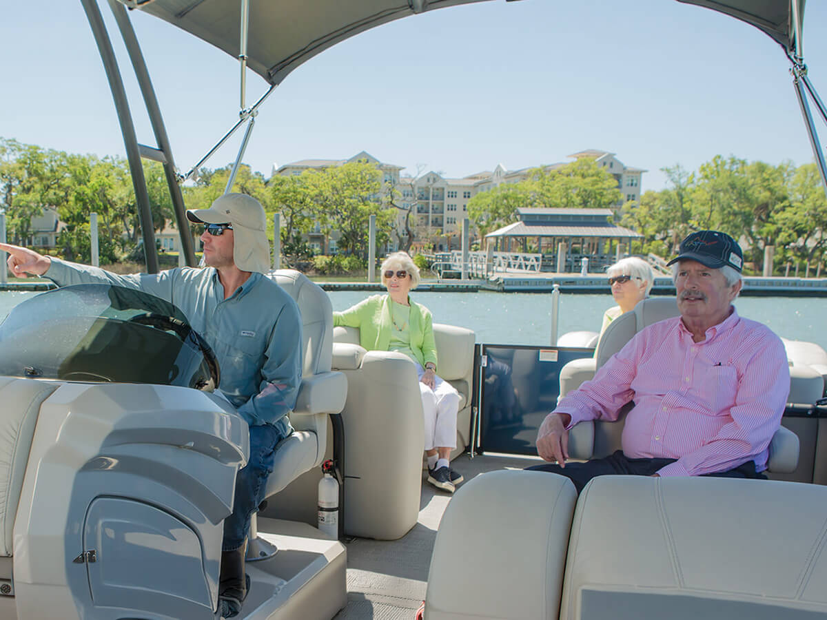 Group enjoying a sunny boat ride near living units overlooking the water.