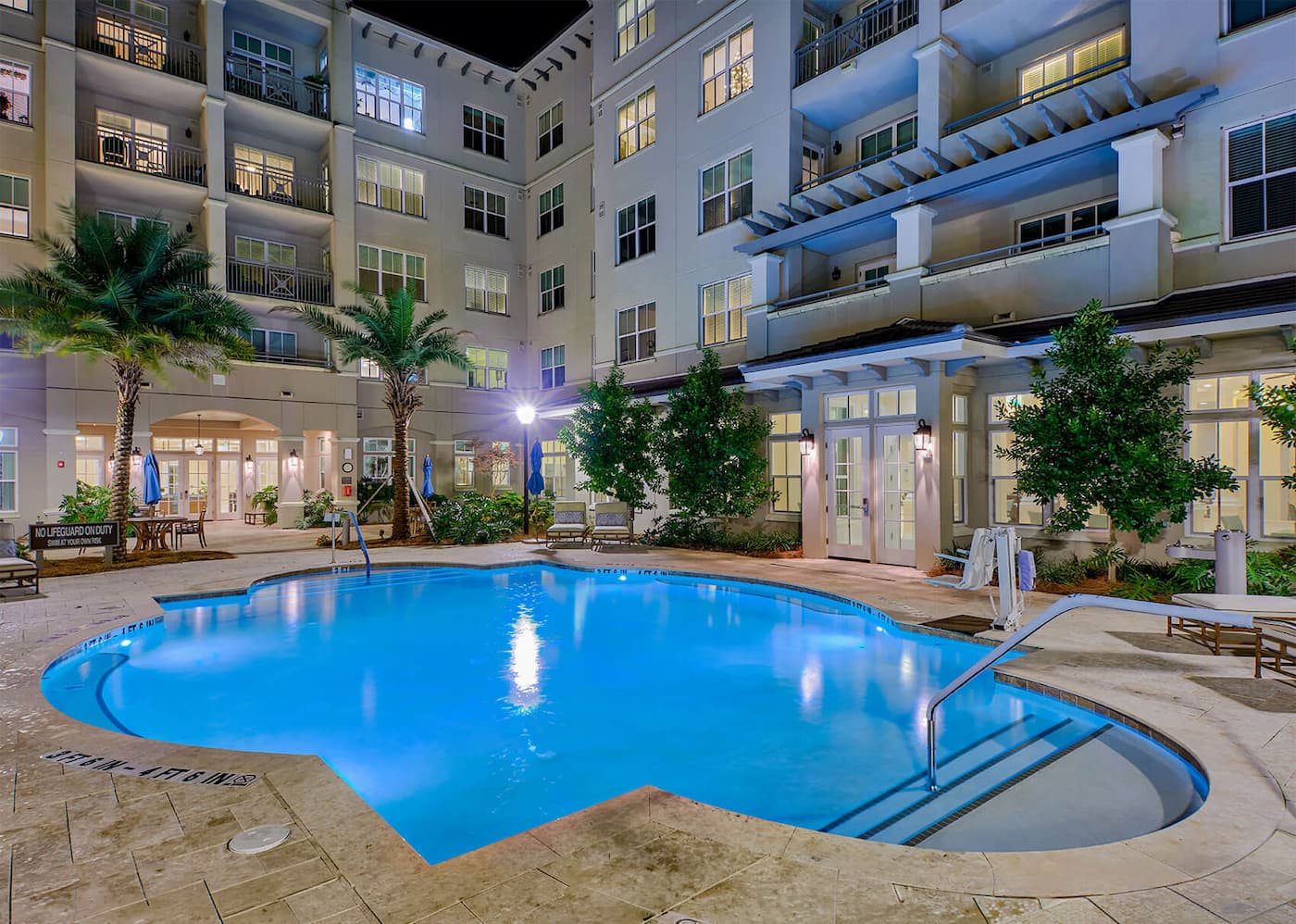 Outdoor pool area with loungers and palm trees at a residential community.