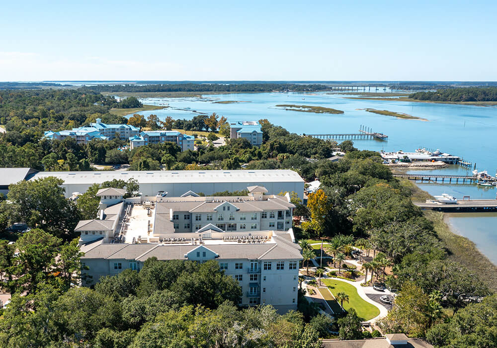 Aerial view of a senior living community near scenic waterfront landscape.