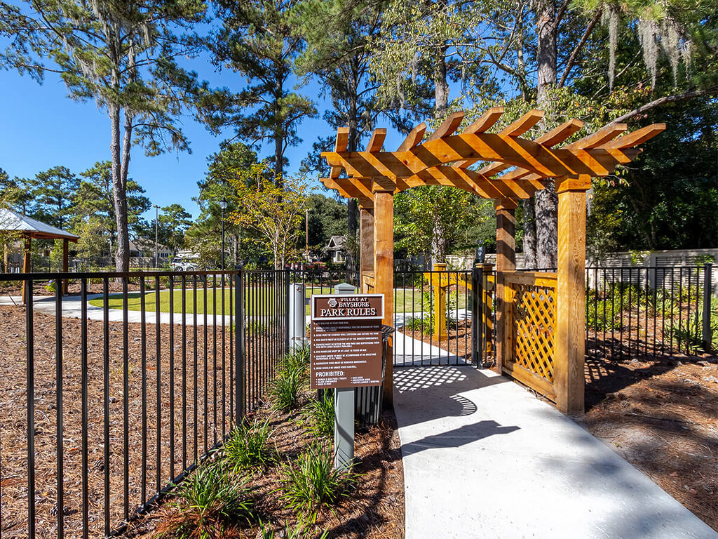 Entrance to a landscaped park area with gate and wooden archway in a senior community.
