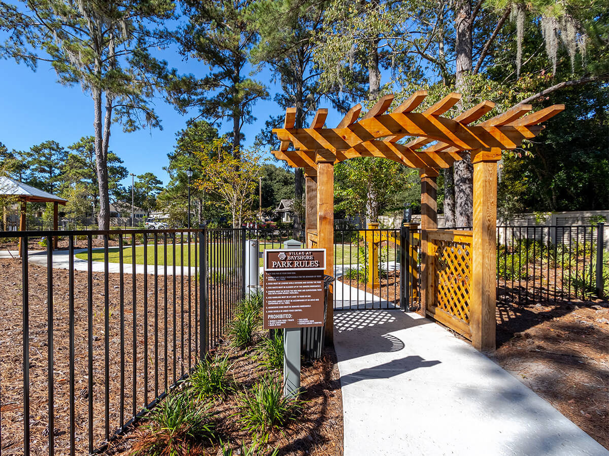 Entrance to a landscaped park area with gate and wooden archway in a senior community.