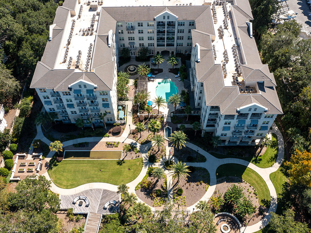 Aerial view of a senior living community with lush gardens and a central pool.