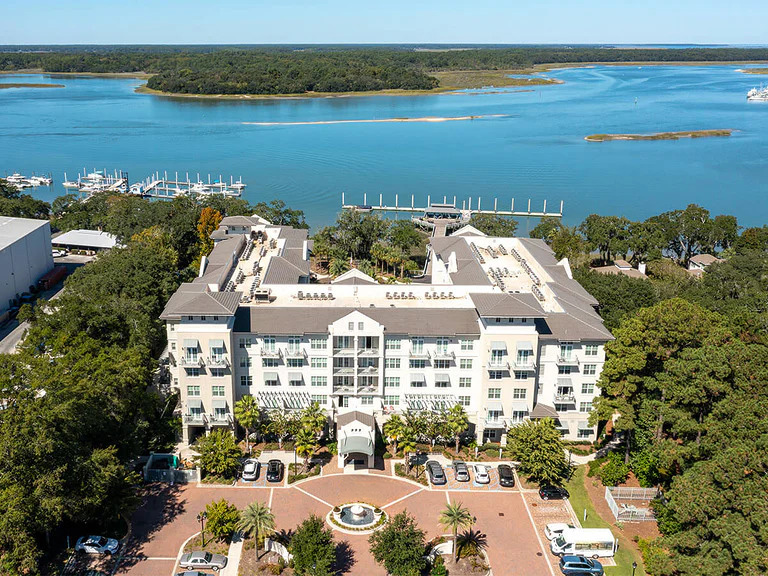 Aerial view of a waterside senior living community with a marina nearby.